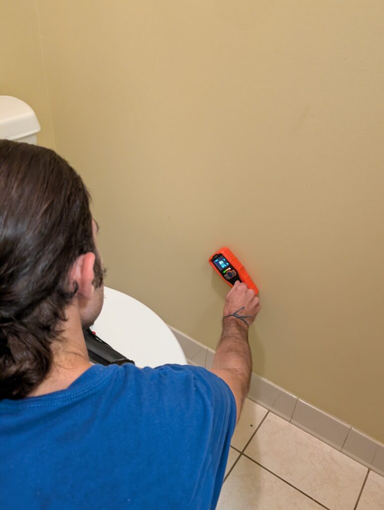 Technician using moisture meter on interior wall to check for water damage in Palm Beach County