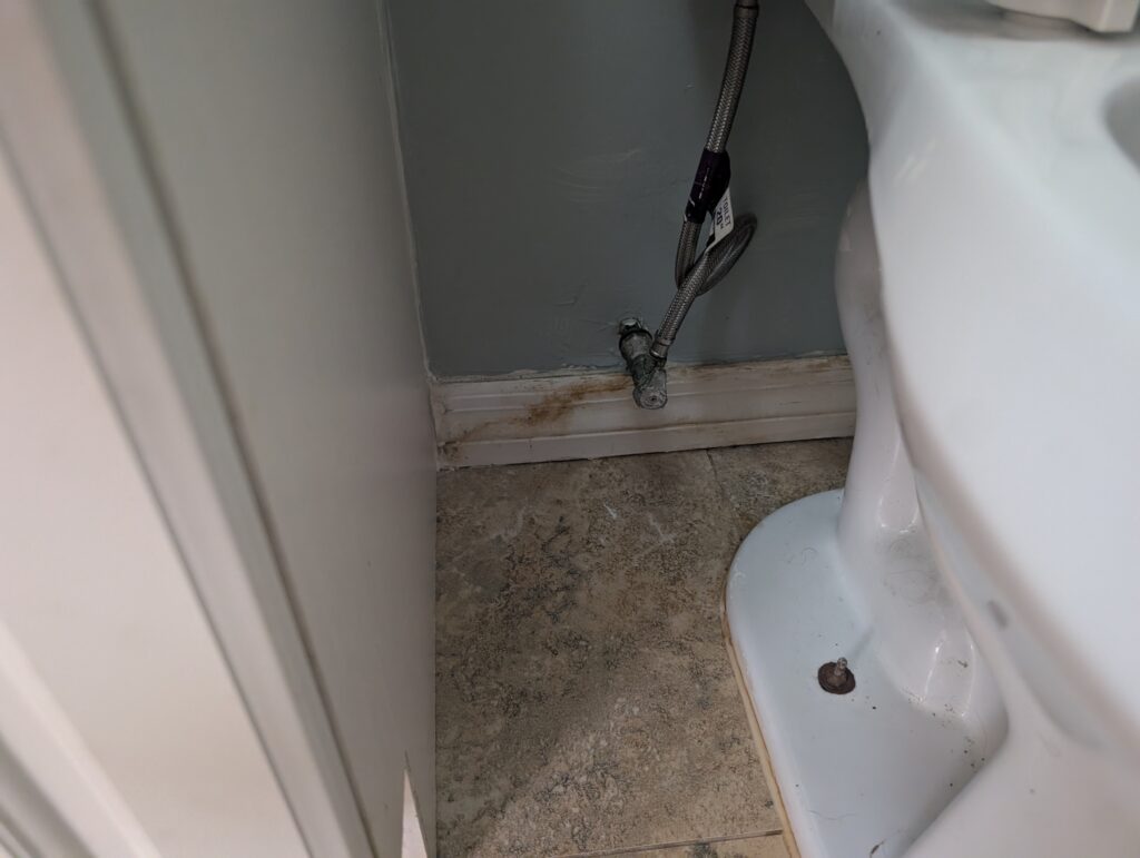 Water damage near a toilet and baseboard caused by a plumbing leak in a Palm Beach County home