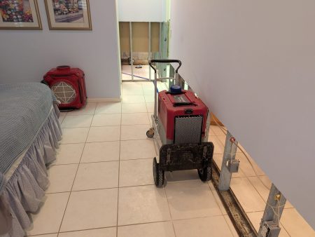 Wall drying setup with baseboards removed and dehumidifier in Palm Beach County home