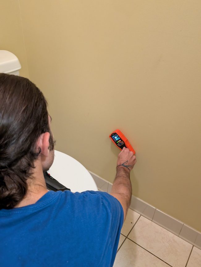 Technician using moisture meter on interior wall to check for water damage in Palm Beach County