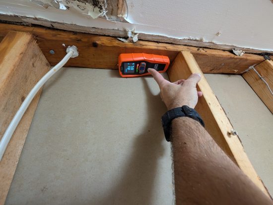 Moisture meter detecting hidden water inside wall framing in Palm Beach County home