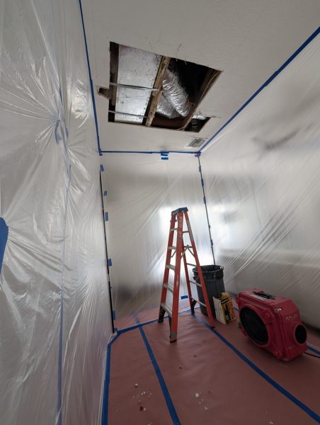 Mold remediation containment setup with plastic barriers and air scrubber in Delray Beach home