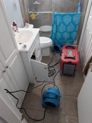air mover and commercial dehumidifier drying bathroom after water damage
