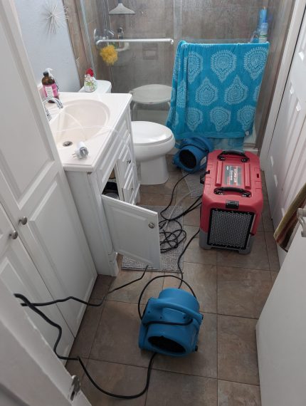 air mover and commercial dehumidifier drying bathroom after water damage