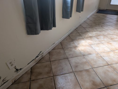 Water damage along baseboard and tile flooring from moisture intrusion in a Palm Beach County home
