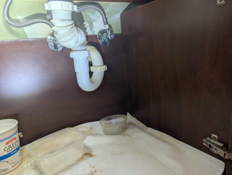 Water damage under kitchen sink cabinet from slow plumbing leak in Palm Beach County home